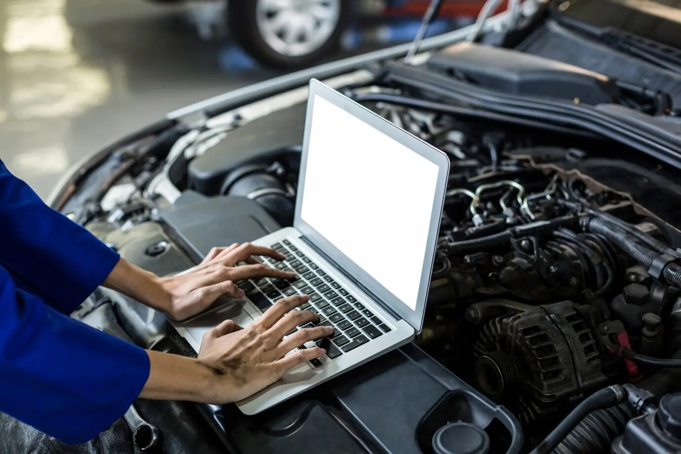 A female mechanic’s hands operating a laptop.