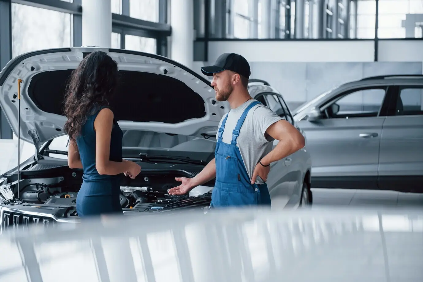 Some details about the accident. A woman in a car showroom with an employee in a blue uniform is taking back her repaired car.
