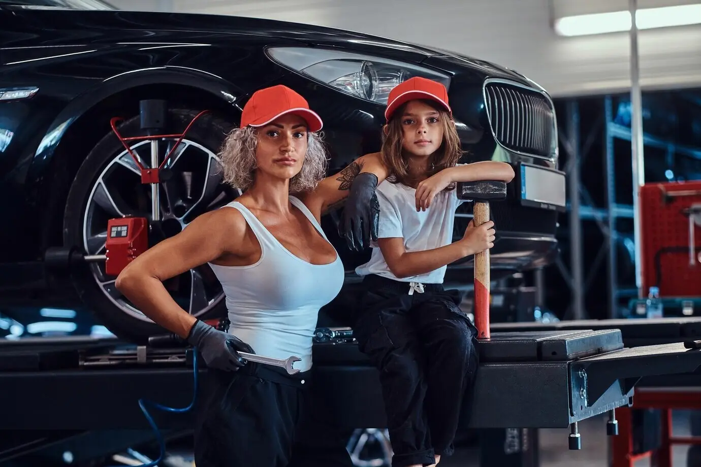 A courageous, strong woman and her little helper are posing for a photographer at an auto workshop.