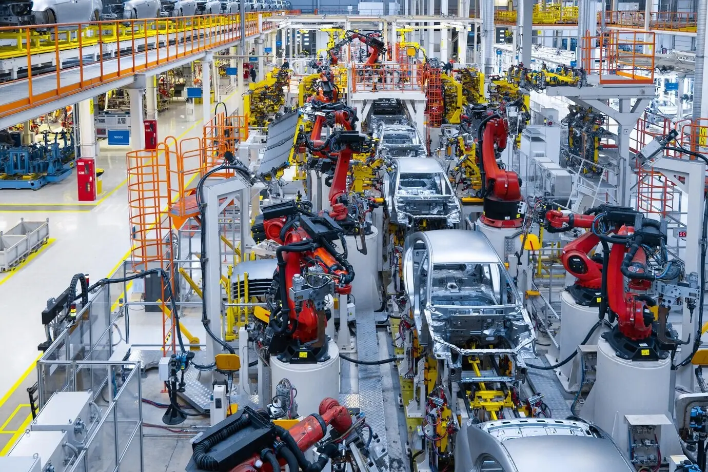 Assembly line manufacturing of a new car; automated welding of the car body with a robotic arm working on the production line.