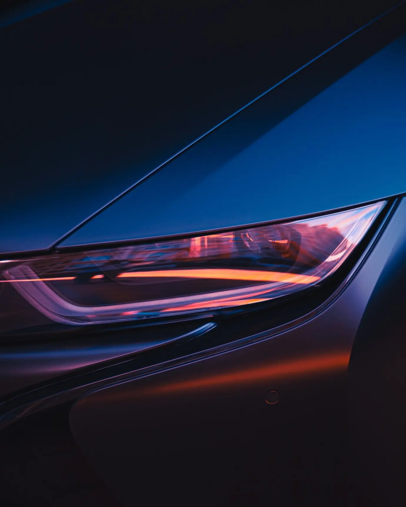 A car’s headlight with buildings reflected in it.