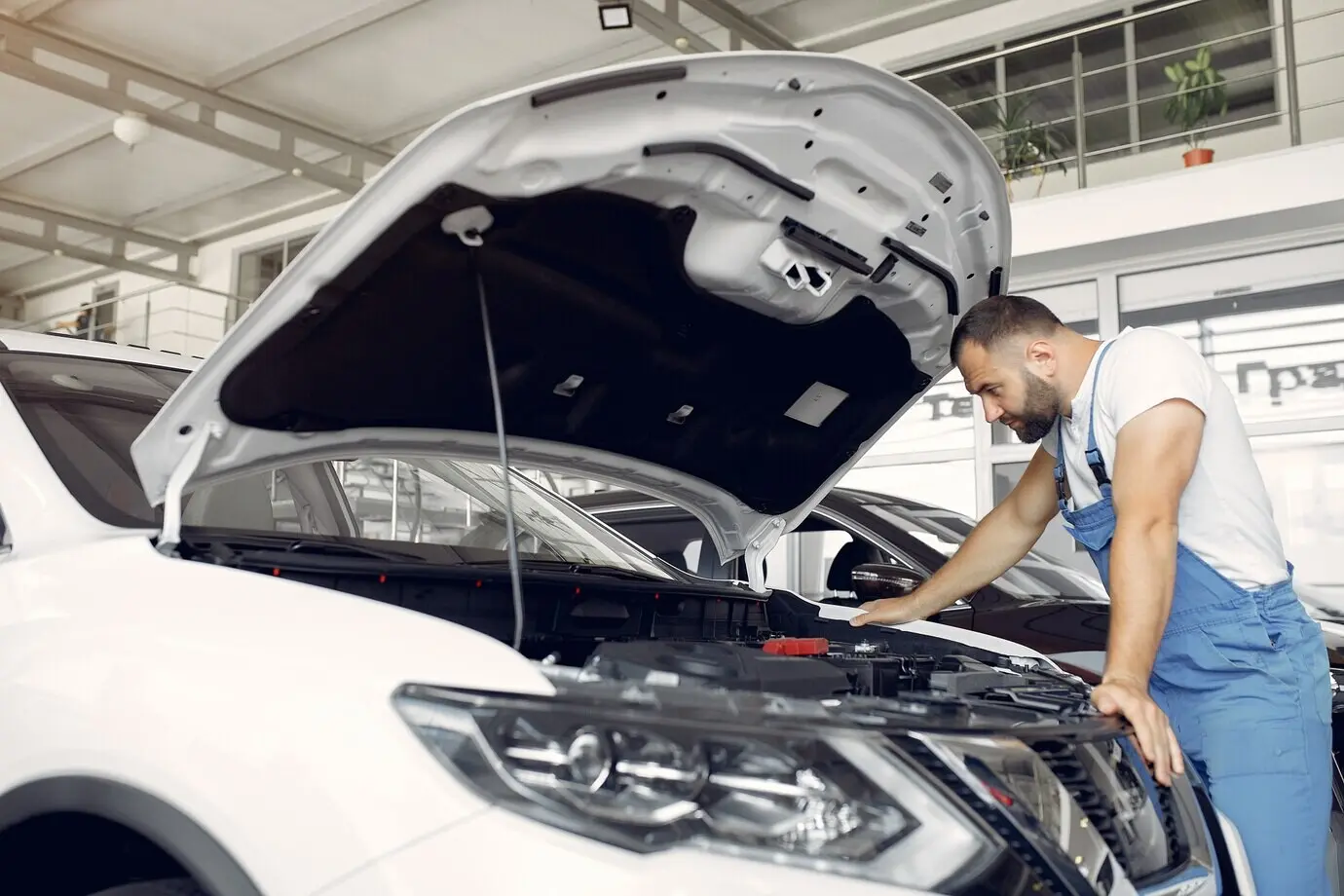 A handsome man in a blue uniform inspects the car.