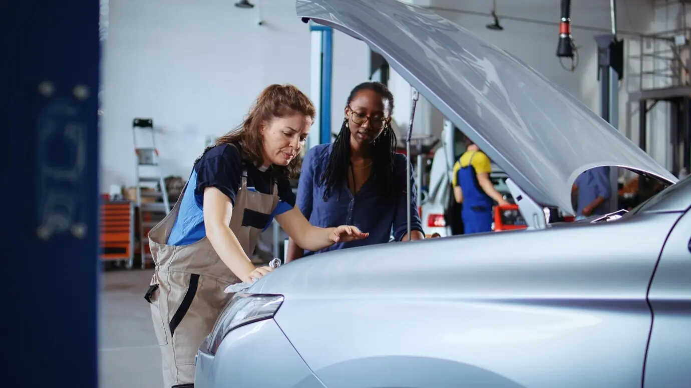 A repairman in a garage cleans a customer's car.